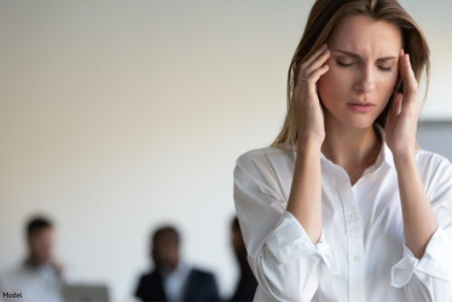 Woman touching her temples looking stressed in an office