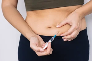 a woman injects bioidentical hormone replacement in her abdomen